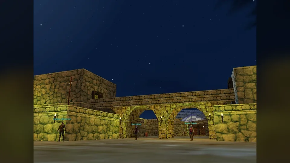 A night view of a stone gateway in Freeport with guard characters standing under torches and name tags above them.