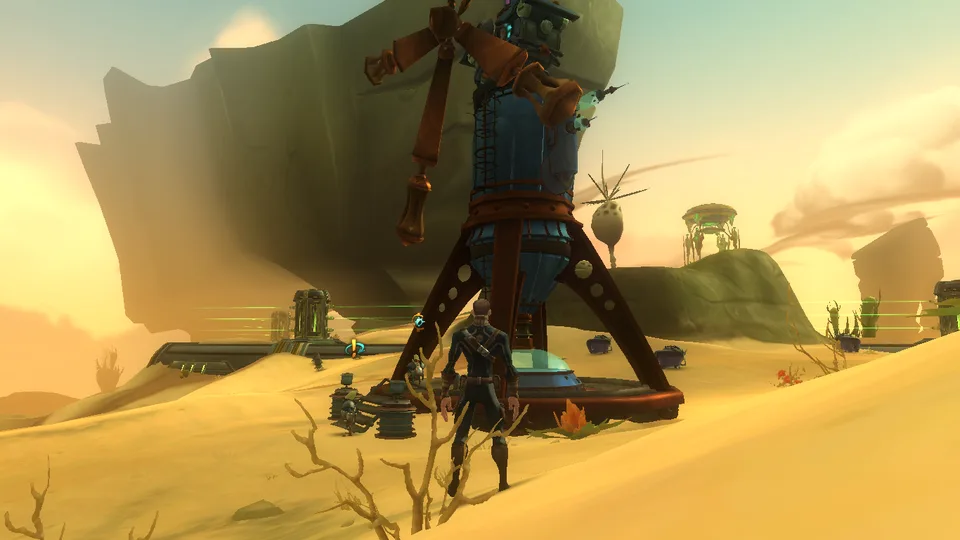 A player character stands beside a tall wind-powered tower on a sandy desert dune under a hazy yellow sky.