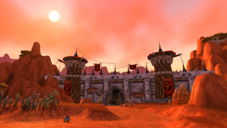 The Horde-banner watchtowers and gate of Orgrimmar in the red Durotar desert at sunset.